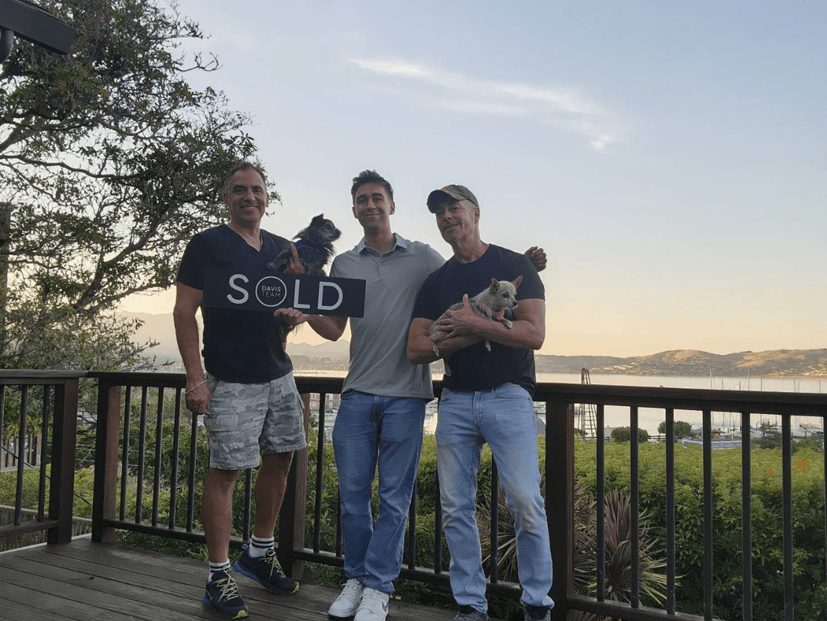 Clients celebrating a sale on a deck overlooking the bay at sunset