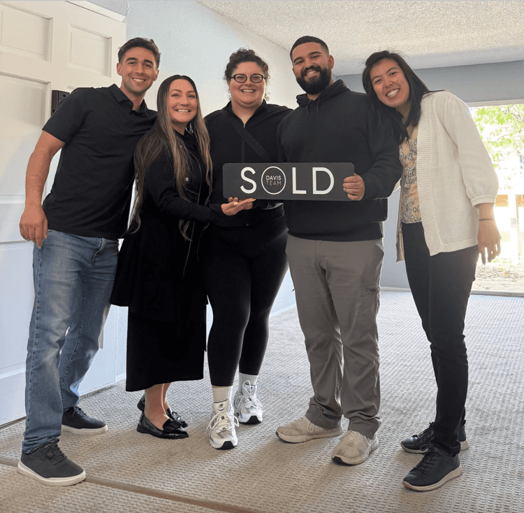 Clients holding a sold sign in their new home