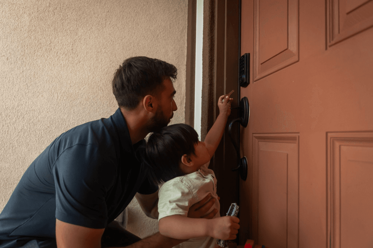 Jaden kneeling with a young child as they unlock the door of a new home