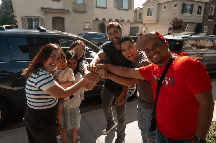Jaden handing keys to a family outside their new home