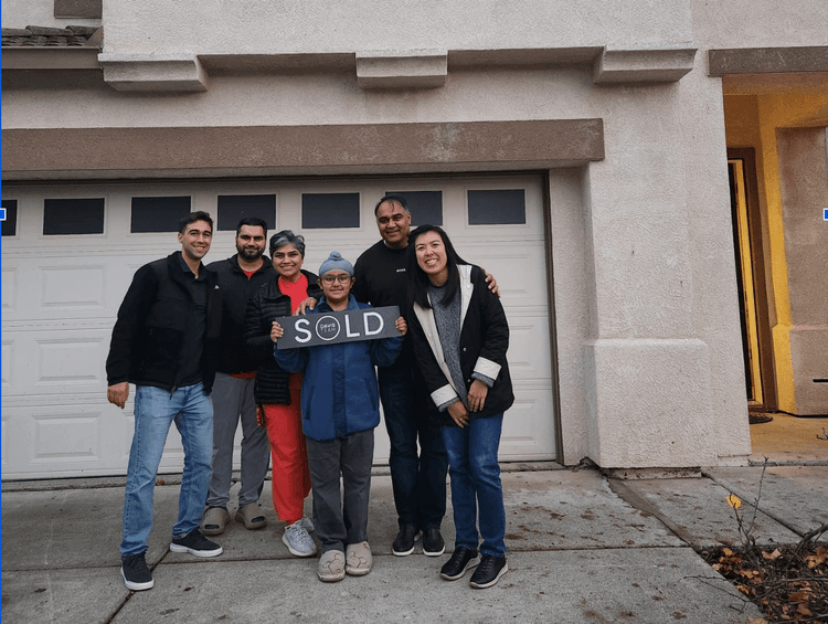 Buyers holding a sold sign outside their new home